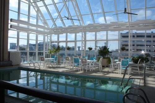 una piscina con sillas y mesas en un edificio en Four Sails Resort, en Virginia Beach