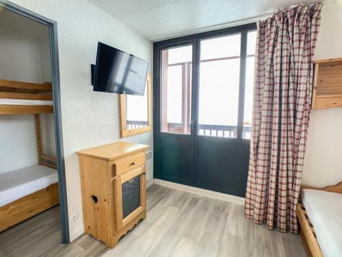 Cette chambre comprend un lit, une télévision et une fenêtre. dans l'établissement Appartement 6 pers. à Tignes Val Claret - Accès direct aux pistes, balcon, animaux acceptés - FR-1-502-289, à Tignes