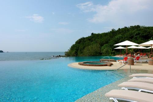a pool with chairs and umbrellas next to the ocean at Azul Ixtapa Grand All Inclusive Suites - Spa & Convention Center in Ixtapa