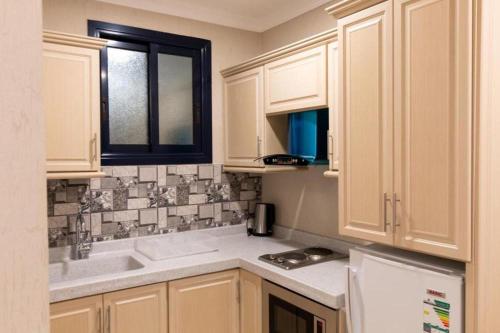 a kitchen with white cabinets and a sink at بيوتات الحور للشقق المخدومة in Taif