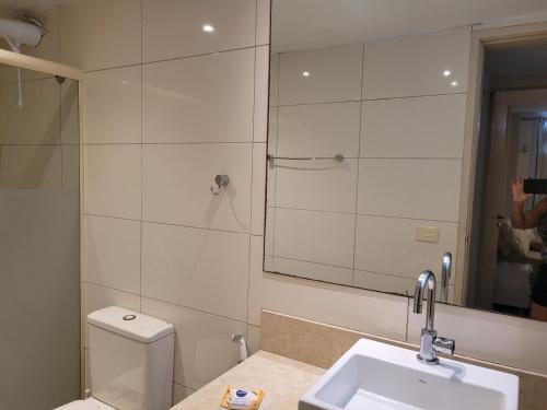 uma casa de banho com um WC, um lavatório e um espelho. em Apartamento em Niterói - Boa Viagem em Niterói