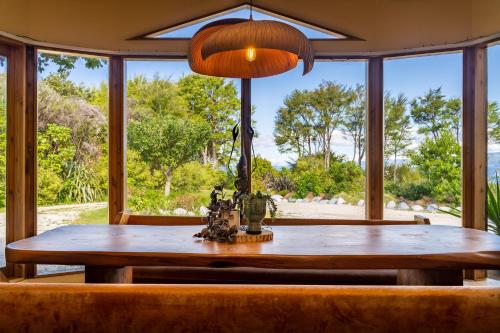 un tavolo da pranzo con sedie e una grande finestra di Ao Marama Retreat a Collingwood