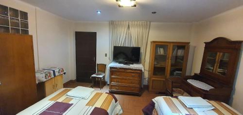 1 dormitorio con 2 camas, TV y tocador en Casa Familiar Munaypatita en Sucre