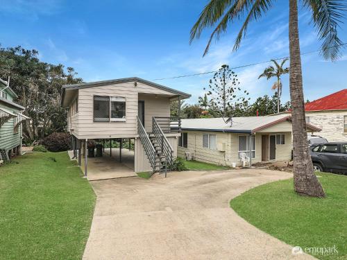 a house with a palm tree and a driveway at Sea Breeze On Archer! in Emu Park