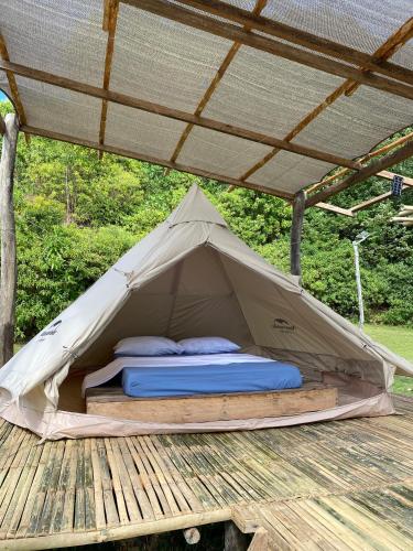 a bed in a tent on a wooden deck at CED Farm in El Nido