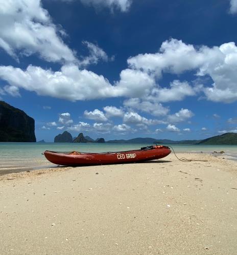 a red boat sitting on the sand on a beach at CED Farm in El Nido