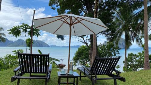 two chairs and a table with an umbrella at CED Farm in El Nido