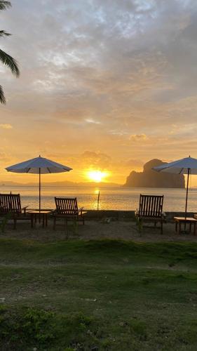 a group of benches and umbrellas on the beach at CED Farm in El Nido