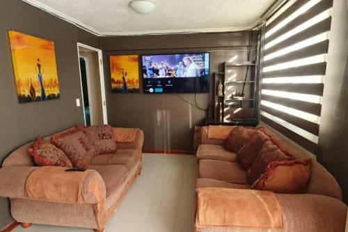 sala de estar con 2 sofás y TV de pantalla plana en Departamento en Dichato, 4 personas frente a la playa, en Dichato