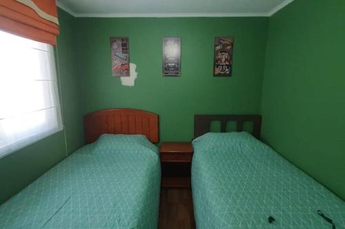 - 2 lits dans une chambre aux murs verts dans l'établissement Departamento en Dichato, 4 personas frente a la playa, à Dichato