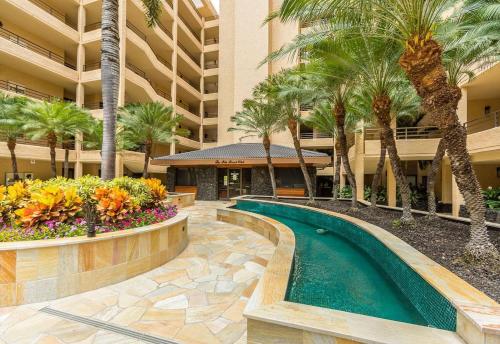 a swimming pool in a resort with palm trees and a building at Polo Beach Club One Bedrooms by Coldwell Banker Island Vacations in Wailea