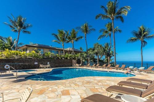 a swimming pool with chairs and palm trees at Polo Beach Club One Bedrooms by Coldwell Banker Island Vacations in Wailea