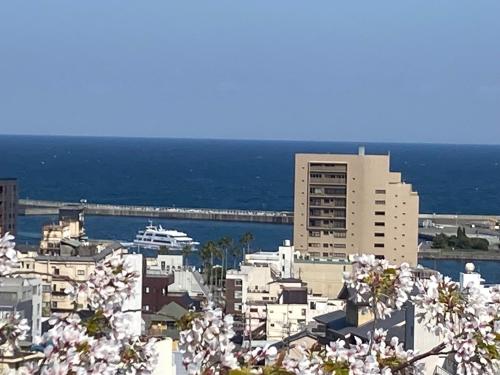 a view of a city with flowering trees and the ocean at ヴィラマーレ熱海（Villa Mare Atami） in Atami