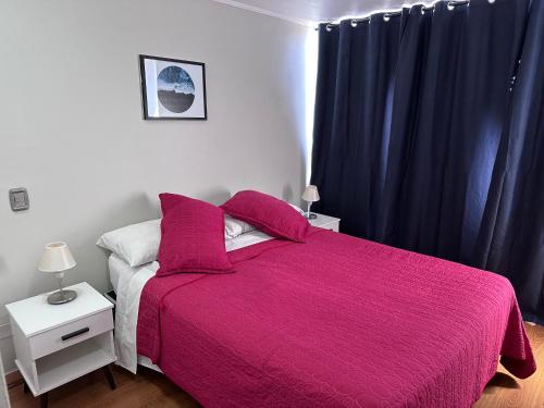 1 dormitorio con 1 cama grande con manta rosa en Departamentos Pontoni Manquehue, en Santiago