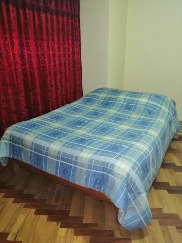 a bed with a blue plaid blanket in a room at Chepita´s House in Puno