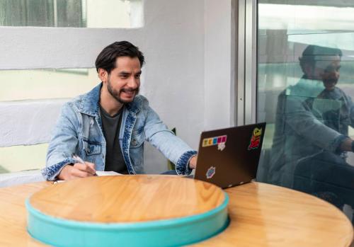a man sitting at a table with a laptop at NATIVUS Art-Hostel in San José