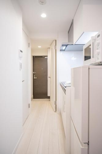 a kitchen with white cabinets and a hallway at Real Okubo Apartment Hotel in Tokyo