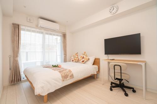 a bedroom with a bed and a desk with a television at リアル大久保　Apartment Hotel in Tokyo