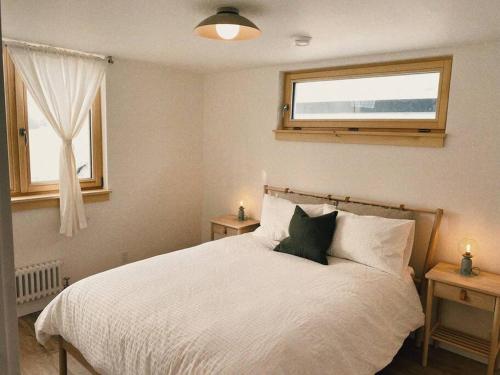 a bedroom with a white bed with a window at The Burrow - Downtown Revelstoke in Revelstoke