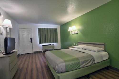 a green bedroom with a bed and a flat screen tv at Motel 6-Tallahassee, FL - Downtown in Tallahassee