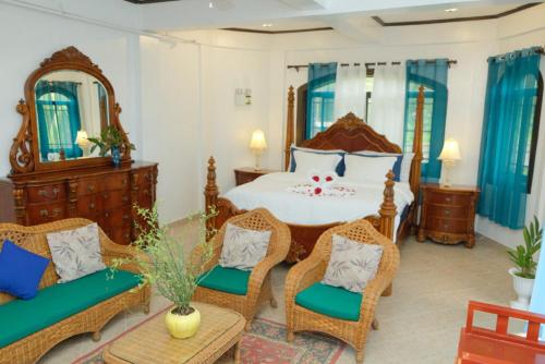 a bedroom with a large bed with wicker chairs at Villa Italia Hotel in Sorsogon
