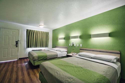 two beds in a room with green walls at Motel 6-Tallahassee, FL - Downtown in Tallahassee