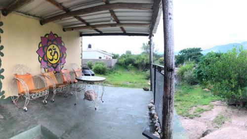 une terrasse avec des chaises et une table ornée d'une peinture murale. dans l'établissement Hosteria Dharma, à Capilla del Monte