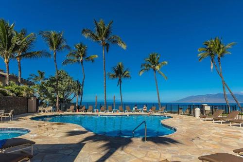 une piscine avec des palmiers et l'océan en arrière-plan dans l'établissement Polo Beach Club Two Bedrooms - Sleeps 4 by Coldwell Banker Island Vacations, à Wailea