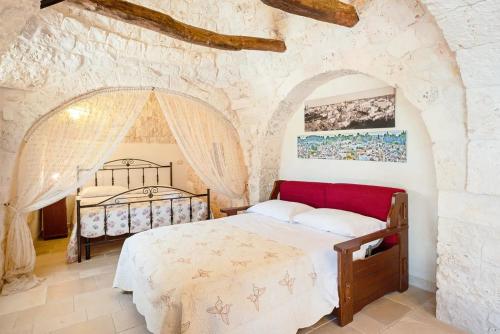 um quarto com uma cama numa parede de pedra em Giardini della Canonica Alberobello em Martina Franca