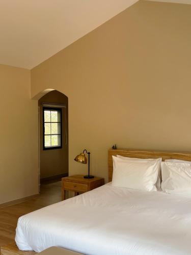 a bedroom with a large white bed and a window at Pink Villa by Tubtao Sleepy Hill in Pong Talong