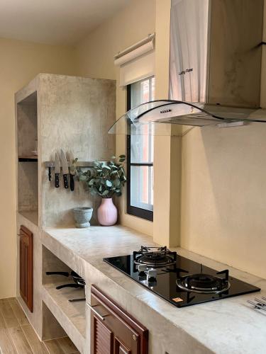 a kitchen with a stove and a counter top at Pink Villa by Tubtao Sleepy Hill in Pong Talong