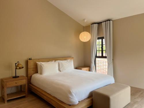 a bedroom with a white bed and a window at Pink Villa by Tubtao Sleepy Hill in Pong Talong