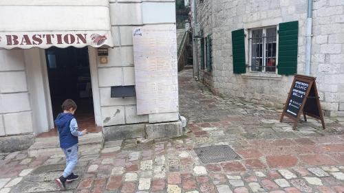 un niño está parado fuera de un edificio en Apartments Đukić en Kotor