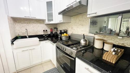 a kitchen with white cabinets and a stove top oven at Sunny Caribbean Apartment with Pool in Punta Cana