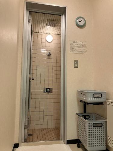 a bathroom with a shower with a clock on the wall at Sapporo International Youth Hostel in Sapporo