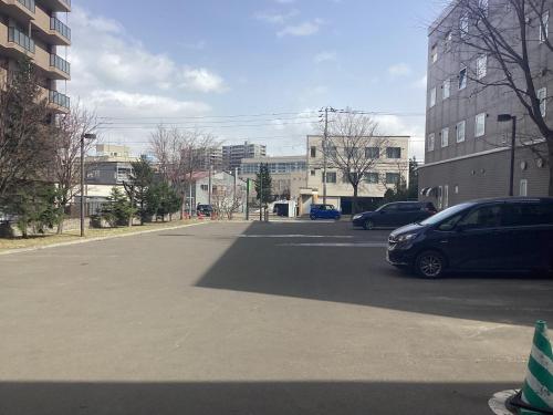 an empty parking lot with cars parked on the street at Sapporo International Youth Hostel in Sapporo