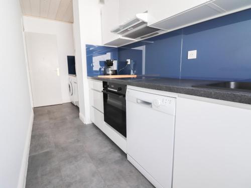 une cuisine avec des armoires blanches et un mur bleu dans l'établissement Appartement skis aux pieds, balcon, 6 pers, Tignes Le Lac - FR-1-502-405, à Tignes