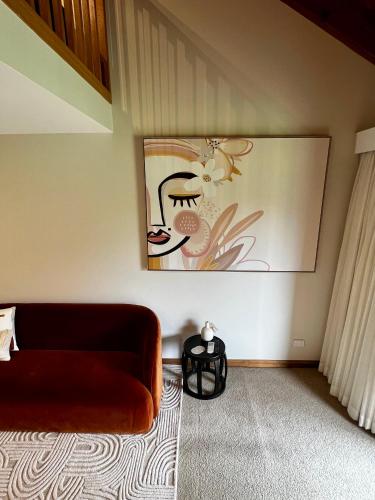 a living room with a couch and a painting on the wall at Hermitage Lodge in Pokolbin