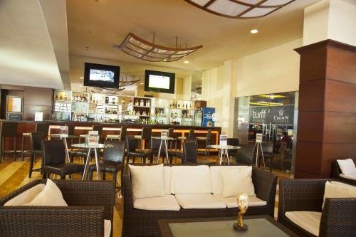 a restaurant with a bar with white couches and tables at Radisson Colon 2,000 Hotel & Casino in Colón