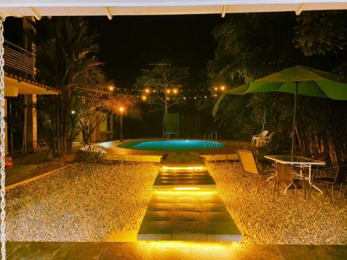 una piscina por la noche con una mesa y una sombrilla en Casa hotel Aeroclubr15, en Villavicencio