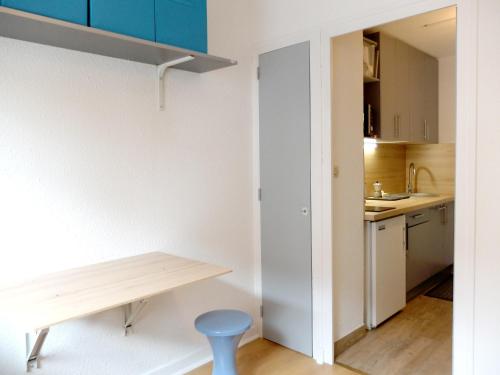 - une petite cuisine avec une table en bois et un tabouret bleu dans l'établissement Studio lumineux proche des pistes avec WIFI - FR-1-502-436, à Tignes