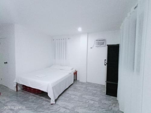 a white room with a bed and a door at Chief's Villa Extension in Malapascua Island