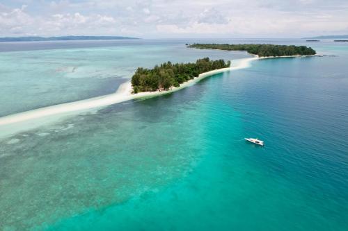 an island in the ocean with a boat in the water at Metita Beach & Dive Resort in Doruba