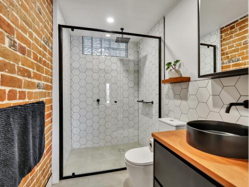 a bathroom with a shower with a sink and a toilet at The Wool Store in Bathurst