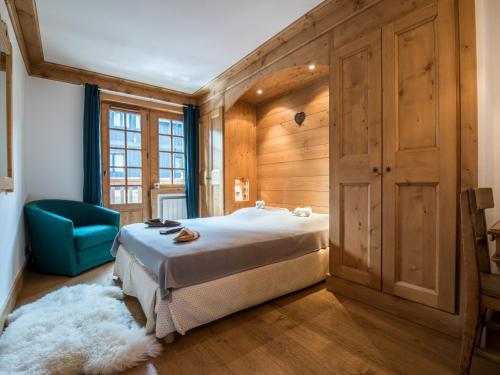 ein Schlafzimmer mit einem Bett und einem blauen Stuhl in der Unterkunft Superbe Duplex 100m² au cœur de Courchevel 1850, à 50m des pistes, 3 chambres, tout confort - FR-1-575-146 in Courchevel