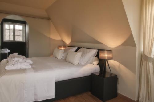 a bedroom with a bed with white sheets and a window at B&B Colombe Blanche in Knokke-Heist