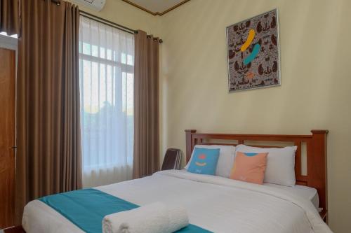 1 dormitorio con 2 camas y ventana en Sans Hotel Kumbang Yogyakarta by RedDoorz en Yogyakarta