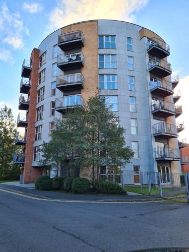 a tall apartment building with a tree in front of it at Eaglet 2 Bedroom Luxury Home near Etihad Staduim in Manchester