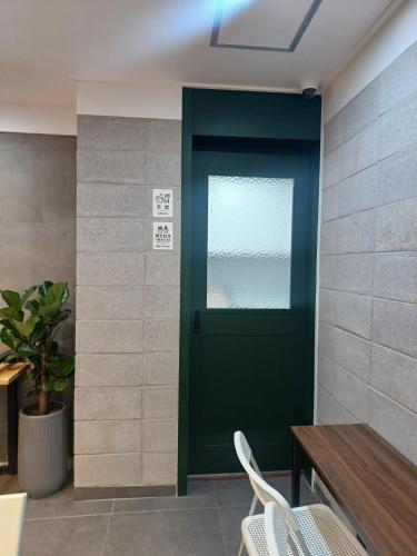 a green door in a room with a table and chairs at Aha Stay in Gyeongju
