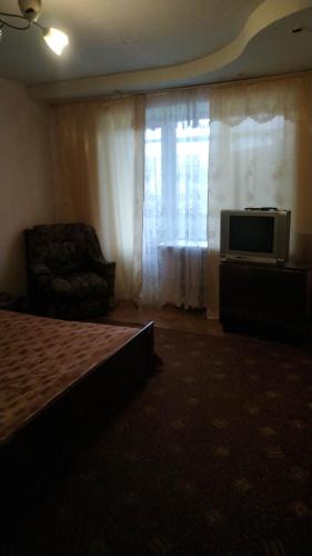 a bedroom with a bed and a television and a chair at Квартиры in Izyum